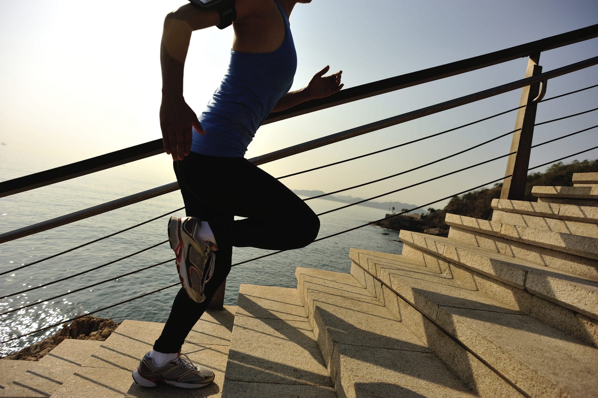 Woman running up stairs next to a beach